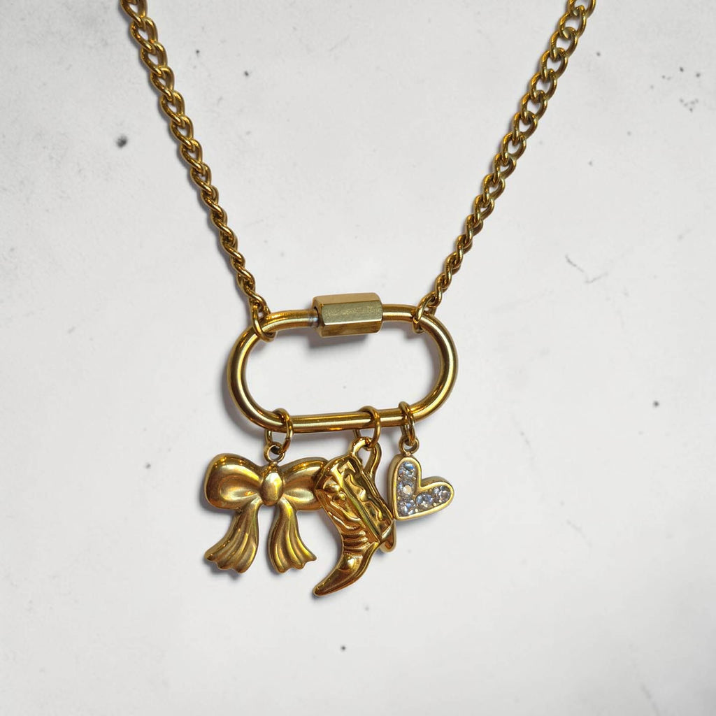 Gold necklace with bow and heart charm on a white background