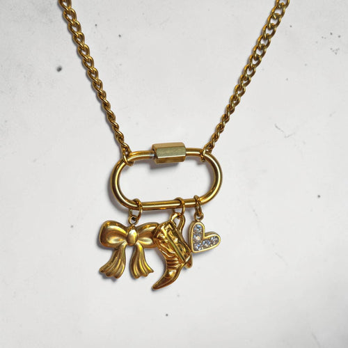 Gold necklace with bow and heart charm on a white background